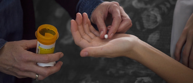 person handing a loved one a prescription opioid