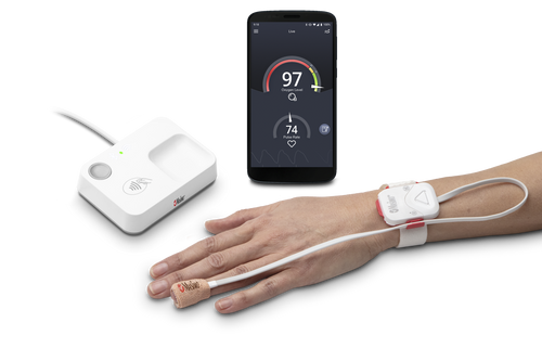 Hand wearing safetynet alert monitor next to home medical hub and a phone displaying Masimo Halo App